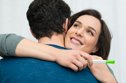Closeup of happy young woman embracing man after positive pregnancy test
