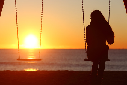 Single woman alone swinging on the beach