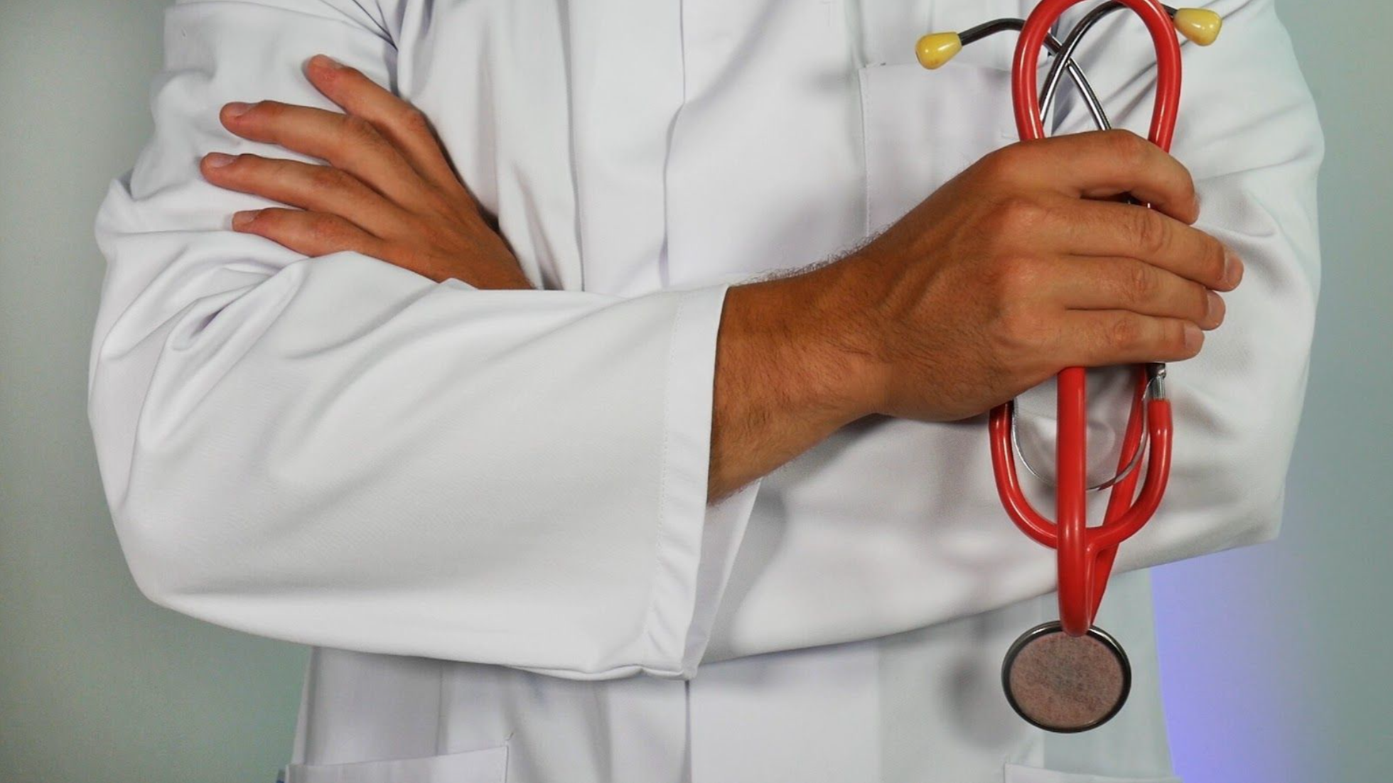 doctor with arms crossed holding a stethoscope